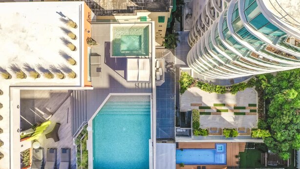 Ein Poolbereich auf dem Dach mit mehreren Schwimmbecken, Liegestühlen und einem modernen architektonischen Design.