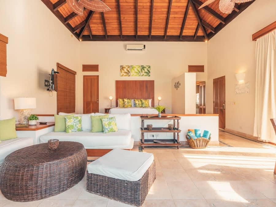 Un vaste espace de vie doté d’un plafond haut, de poutres en bois, d’un ensemble de canapés, d’un pouf en osier et d’une petite table agrémentée d’objets décoratifs.