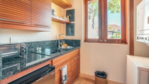 Une cuisine compacte dotée d’un four encastré, d’un évier, de meubles en bois et d’une fenêtre offrant une vue agréable.