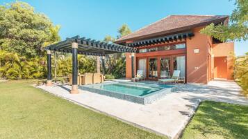 A modern house with a swimming pool, covered patio, and lush greenery.