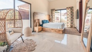 A bedroom with a bed, a hanging chair, a bedside table, and a large window. - Apartment w 2br Close to the Beach at Portillo X (Las Terrenas)