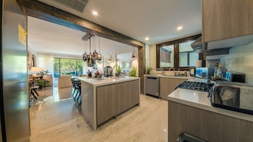 Una cocina moderna con una isla central, electrodomésticos de acero inoxidable y un amplio ventanal.