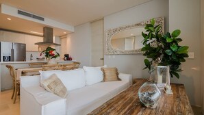 Eine moderne Küche mit weißer Arbeitsplatte, einem Edelstahl-Kühlschrank und einem Essbereich mit Holztisch und weißem Sofa.