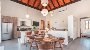 A modern kitchen with a central island, wooden chairs, and a dining table.