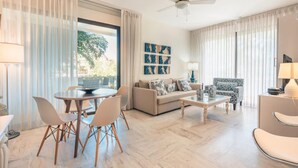Uma sala de estar moderna com sofá, mesa de centro, cadeiras, uma mesa de jantar e um ventilador de teto.