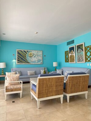 A living room with a blue wall, a sofa, two wicker chairs, and two lamps.