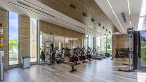 A modern gym with various exercise equipment, large windows, and a clean, organized layout. - 2br 5 Guests Private Balcony and Shared Pool (Cartagena)