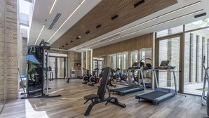 A modern gym with various exercise equipment, large windows, and a wooden floor. - 2br 5 Guests Private Balcony and Shared Pool (Cartagena)