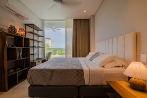 Habitación de hotel moderna con una cama grande, un escritorio, una estantería y vistas a zonas verdes.