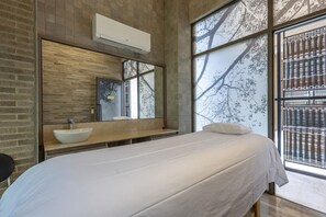 Un dormitorio moderno con una cama grande, un lavabo integrado y un ventanal con vistas a árboles.