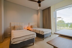 Una habitación de hotel moderna con dos camas, un ventilador de techo, un ventanal con cortinas y vistas al exterior.