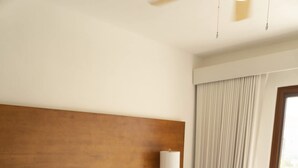 Une chambre d’hôtel avec un grand lit, une tête de lit en bois, une table de chevet avec une lampe et une fenêtre avec des rideaux.