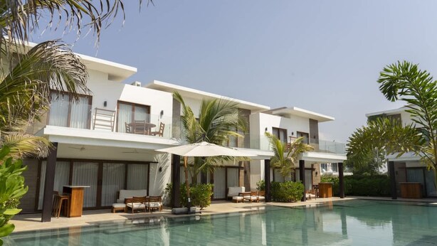 Un hôtel moderne doté d’une piscine, d’un espace extérieur aménagé et de palmiers.