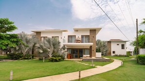 Une maison moderne à deux étages, dotée d’une pelouse bien entretenue, d’un chemin menant à l’entrée et d’un petit espace patio.