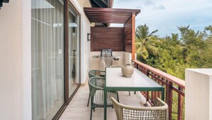 A balcony with a table, chairs, a grill, and a view of greenery. - Apartment w 3br Near the Beach in Portillo Raa (Las Terrenas)