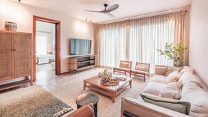 A living room with a sofa, chairs, a coffee table, a television, and a ceiling fan. - Apartment w 3br Near the Beach in Portillo Raa (Las Terrenas)