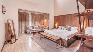 A modern hotel room with a large bed, a sofa, a wooden side table, and a mirror. - Apartment w 3br Near the Beach in Portillo Raa (Las Terrenas)