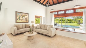 Uma sala de estar espaçosa com dois sofás, uma mesa de centro e uma janela grande com vista para uma piscina.