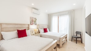 Quarto de hotel com duas camas, uma cadeira, uma televisão e uma janela com cortinas.