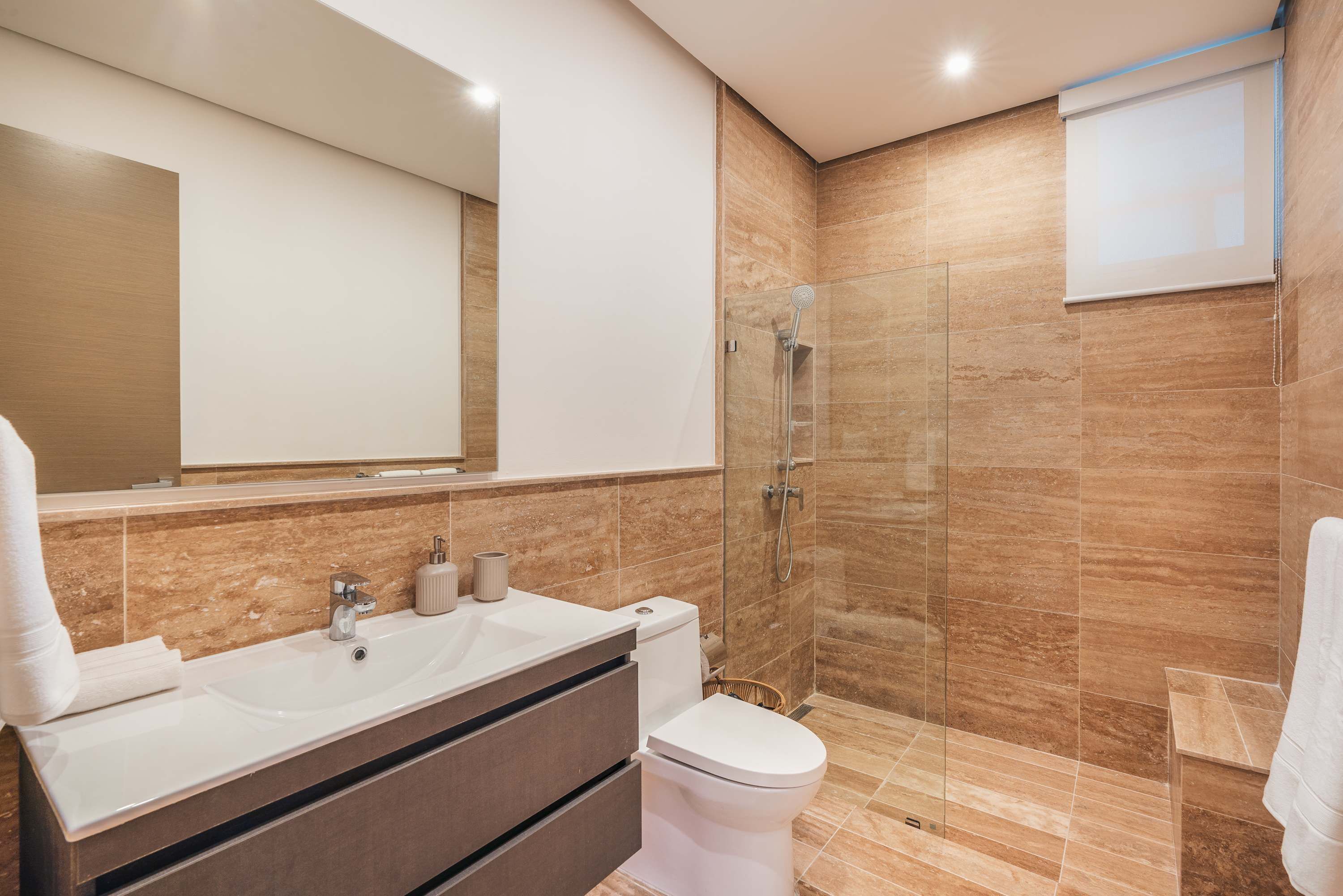 A modern bathroom with a glass shower, a white sink, and a toilet.