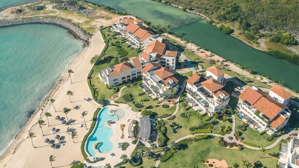 Oversigtsbillede af et resort med flere bygninger, en swimmingpool og en strandpromenade.