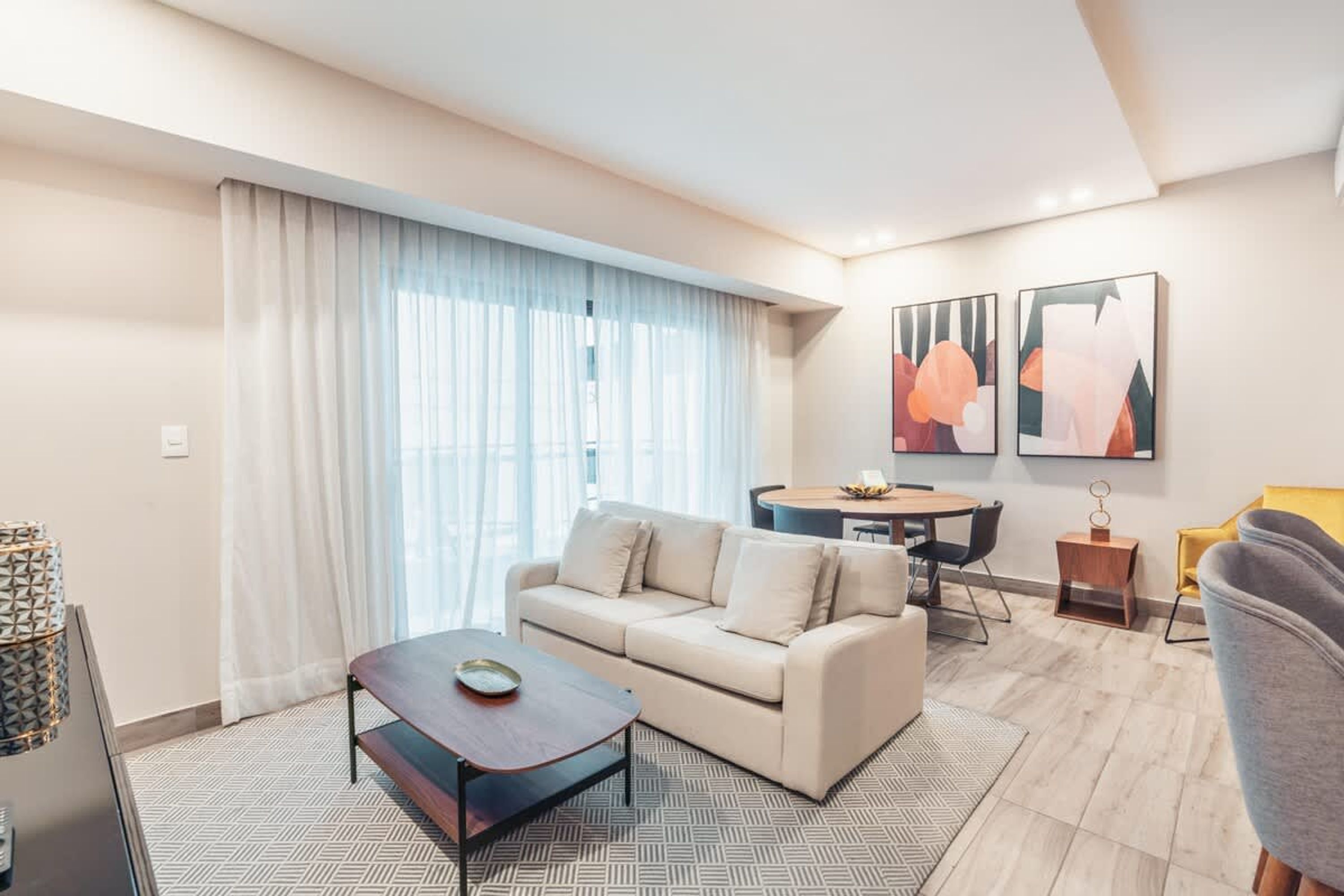 A modern living room with a sofa, coffee table, and dining area.