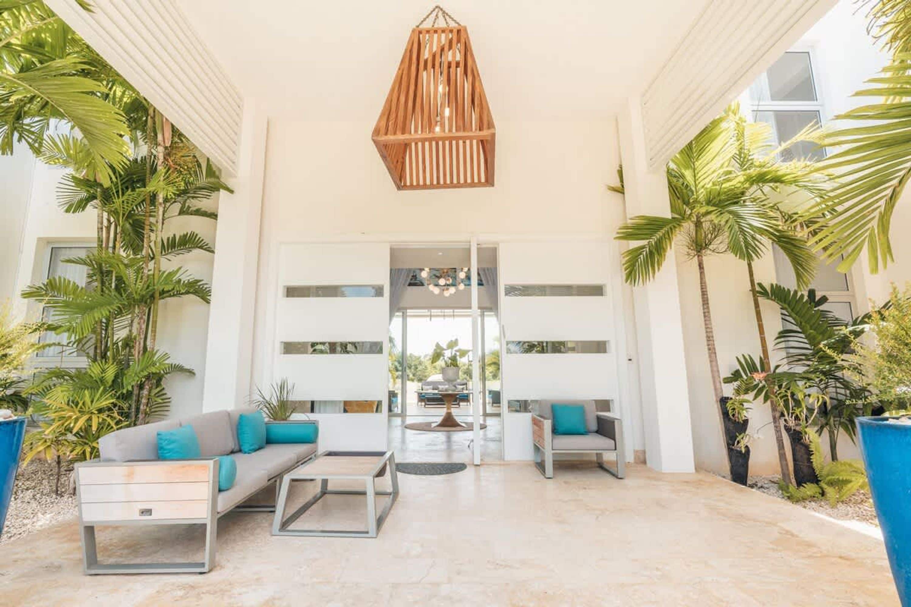 Um lobby moderno com um sofá, cadeiras, uma mesa de centro e um lustre.