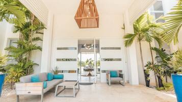 Um lobby moderno com um sofá, cadeiras, uma mesa de centro e um lustre.