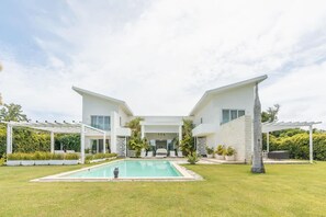 A modern two-story house with a swimming pool, white exterior, and a covered patio area.