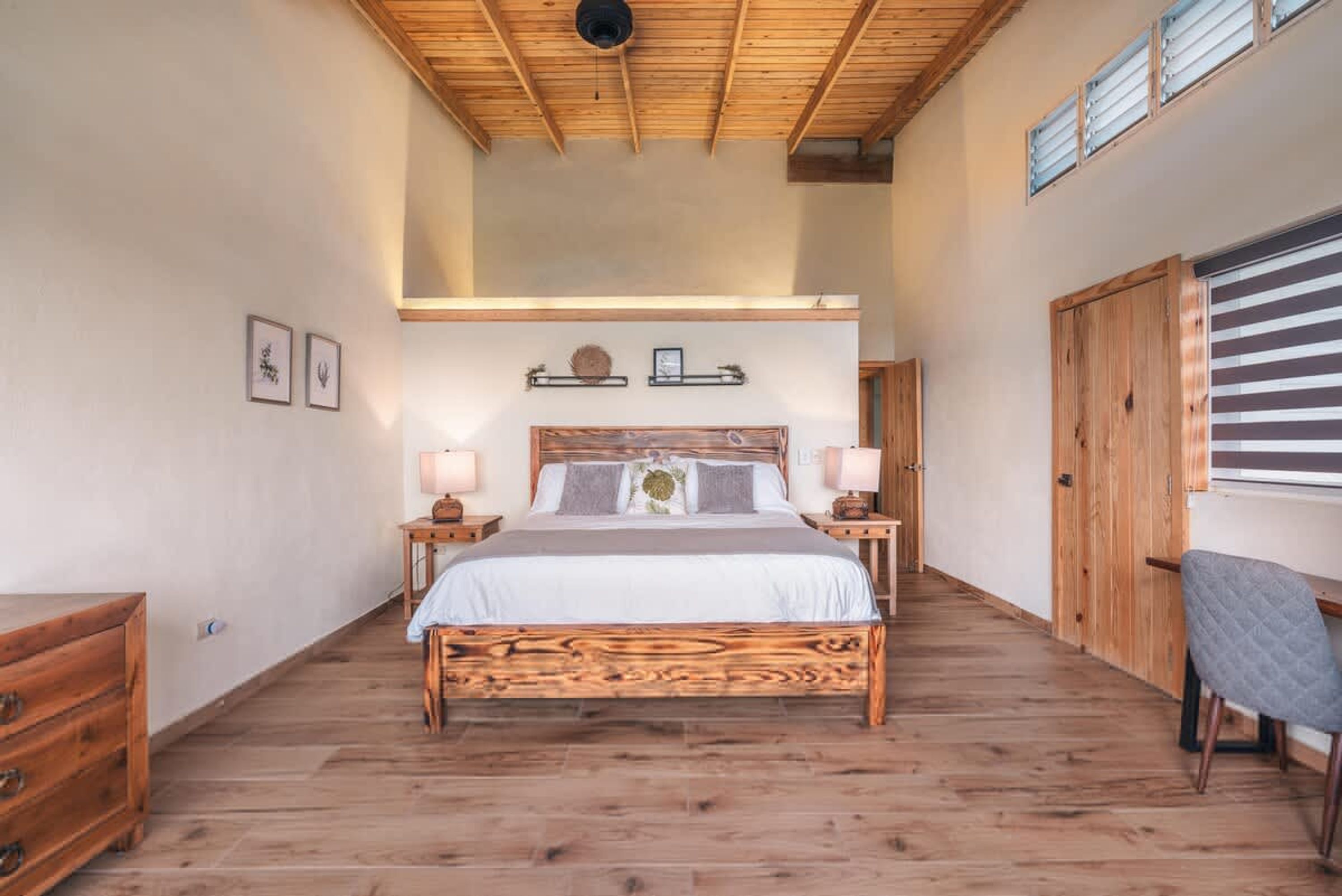 A bedroom with a wooden bed, bedside tables, a wardrobe, and a window with blinds.
