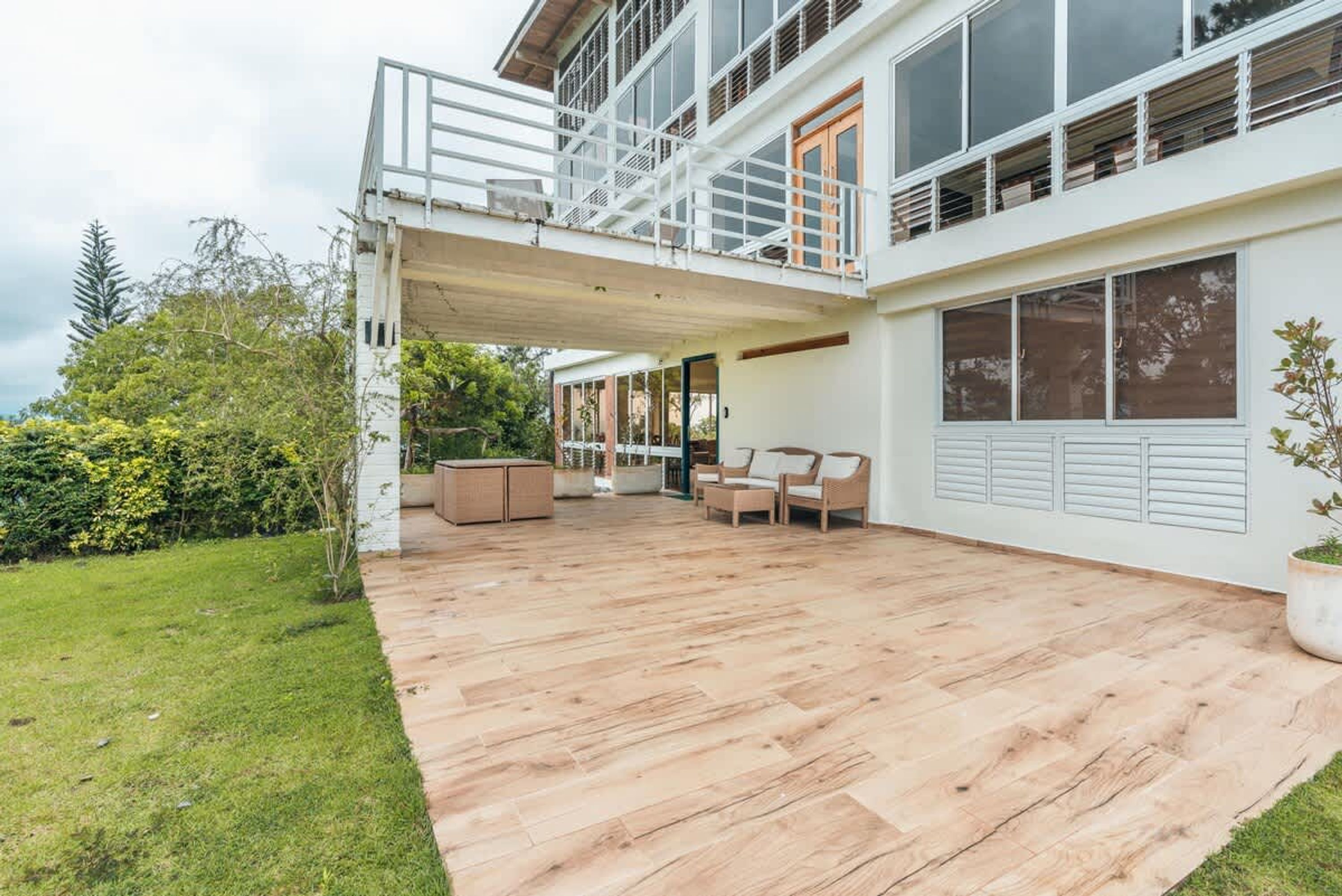 A modern house with a covered patio, outdoor furniture, and a view of the surrounding greenery.