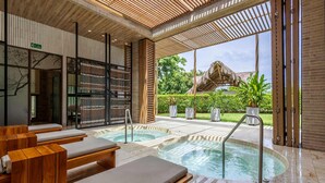 A spa area with wooden loungers, a hot tub, and a view of a thatched-roof structure. - 3-bedroom Apartment With Ocean Views in Baru (Cartagena)