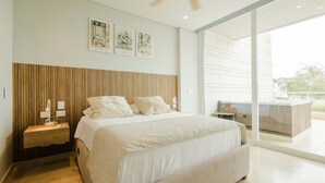 A modern bedroom with a large bed, wooden headboard, bedside lamps, and artwork on the wall. - Two Bedrooms apt With Views in Baru With Jacuzzi (Cartagena)