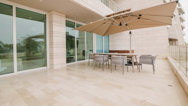 A modern outdoor patio with a table and chairs, a large umbrella, and a glass door leading to a balcony. - Two Bedrooms apt With Views in Baru With Jacuzzi (Cartagena)