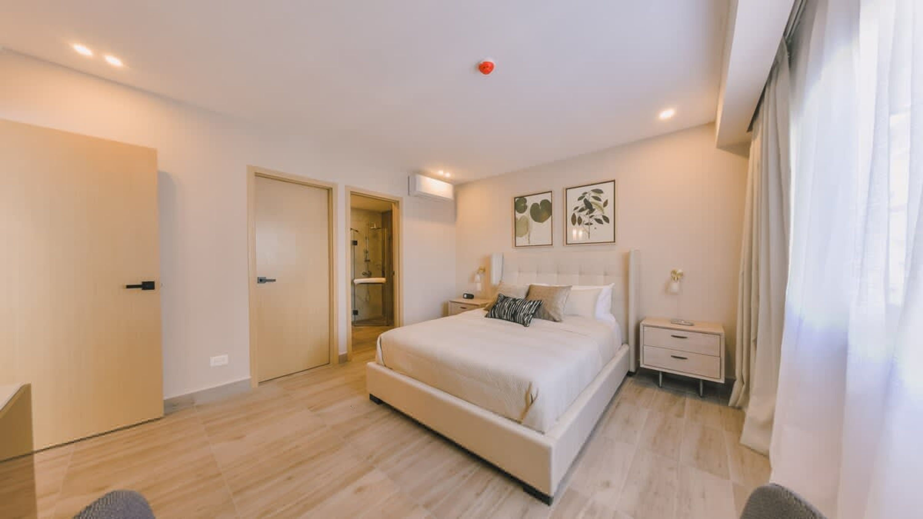 A bedroom with a large bed, bedside tables, a wardrobe, and a shower area.