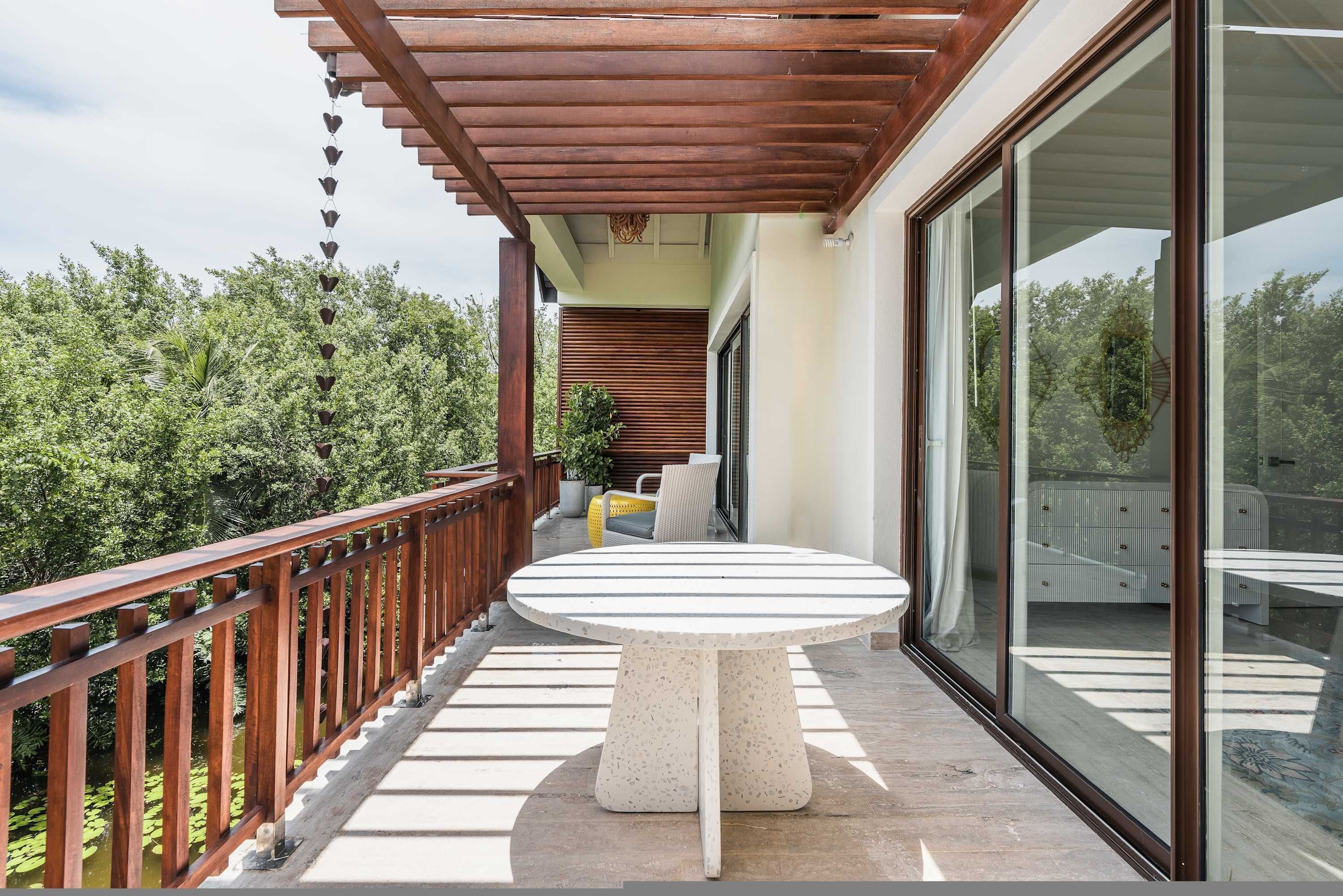 Ein Balkon mit Holzwertkasten, einem runden Tisch und Blick auf Grünflächen.