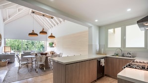 Una cocina moderna con una isla central, armarios de madera e iluminación colgante.