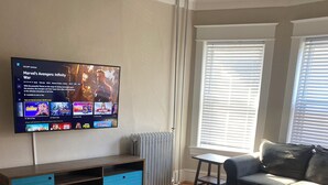 Een woonkamer met een televisie, een bank, een salontafel en een kamerbreed tapijt.