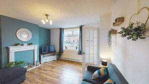 A living room with a fireplace, a television, a sofa, and a view of the street. - Spacious Home Ideal For Families Free Parking (Chester)