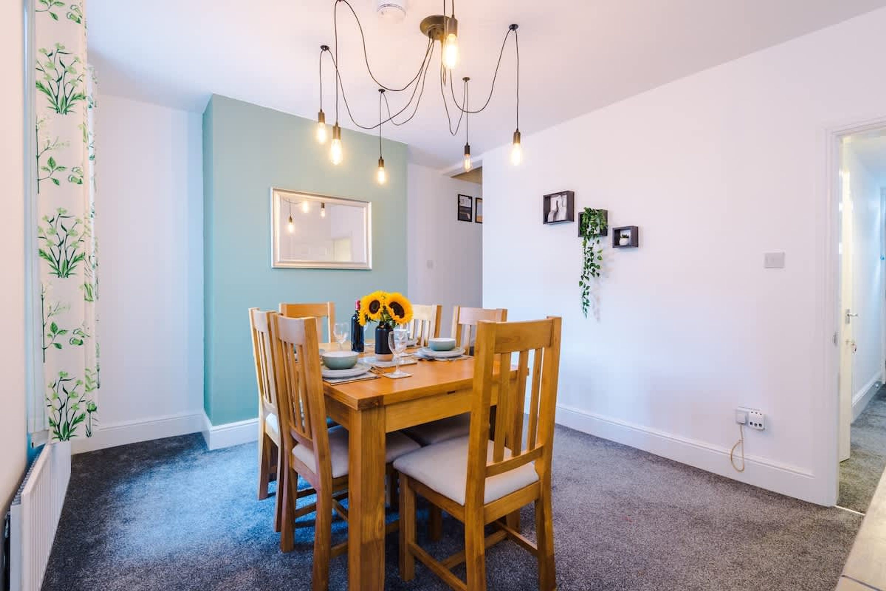 Un comedor con una mesa y sillas de madera, un candelabro y un espejo en la pared.