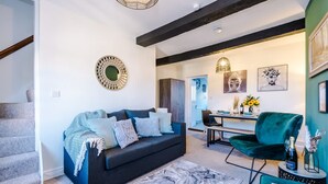 A modern living room with a dark sofa, a green chair, a marble rug, and a dining area with a table and chairs. - Cosy House Amazing Location Perfect for Couples (Chester)