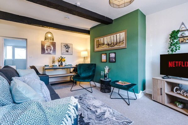 A living room with a sofa, a chair, a TV, and a painting on the wall.