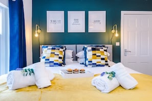 Une chambre d’hôtel avec un lit, des œuvres d’art accrochées au mur et une porte.