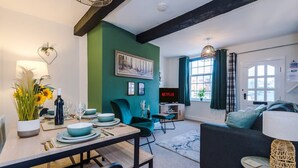 A modern living room with a green accent wall, a dining area with a table set for four, and a sofa. - Cosy House Amazing Location Perfect for Couples (Chester)