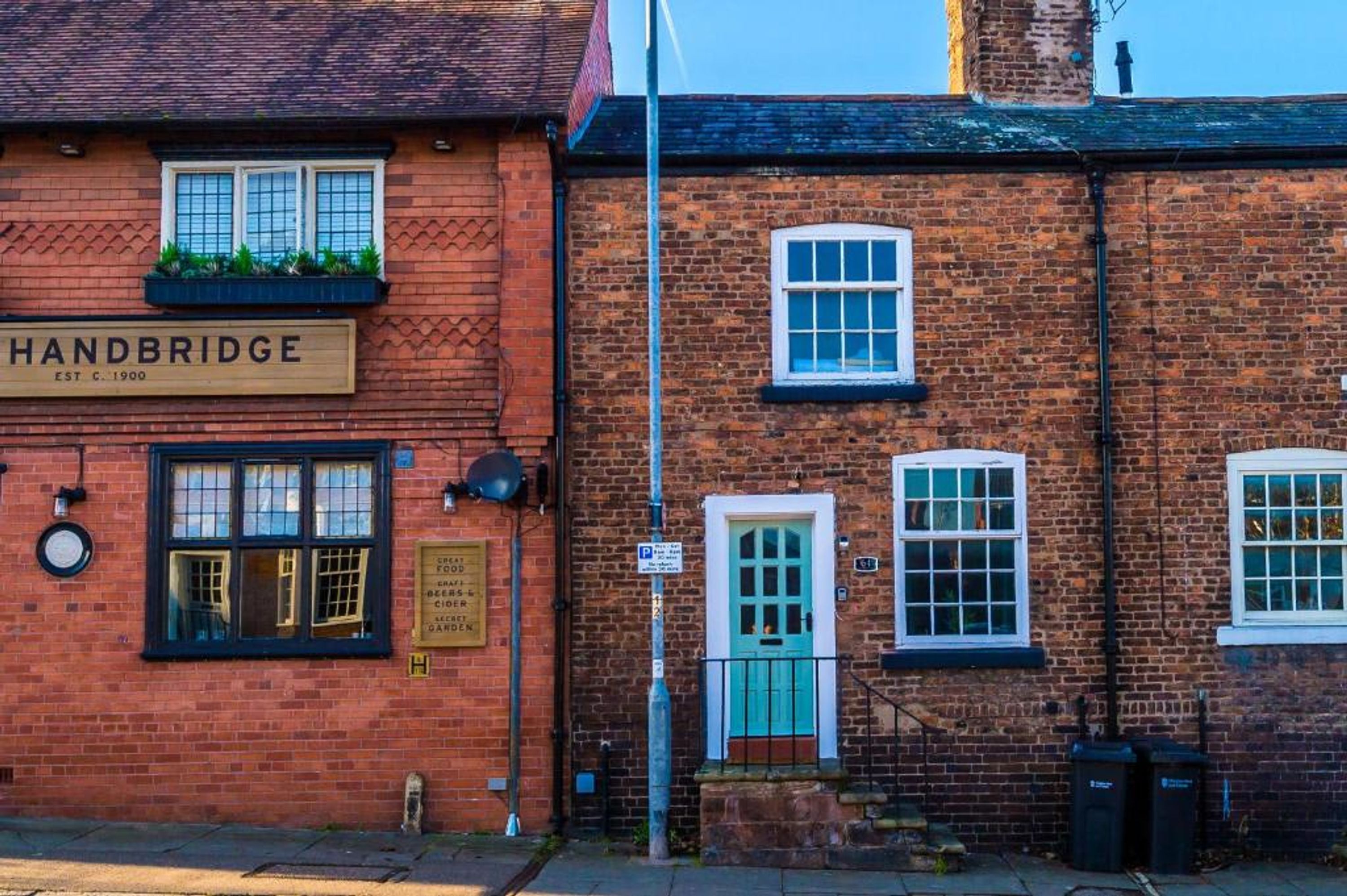 A brick building with a sign reading 'Handbridge' and a small window with a blue door.