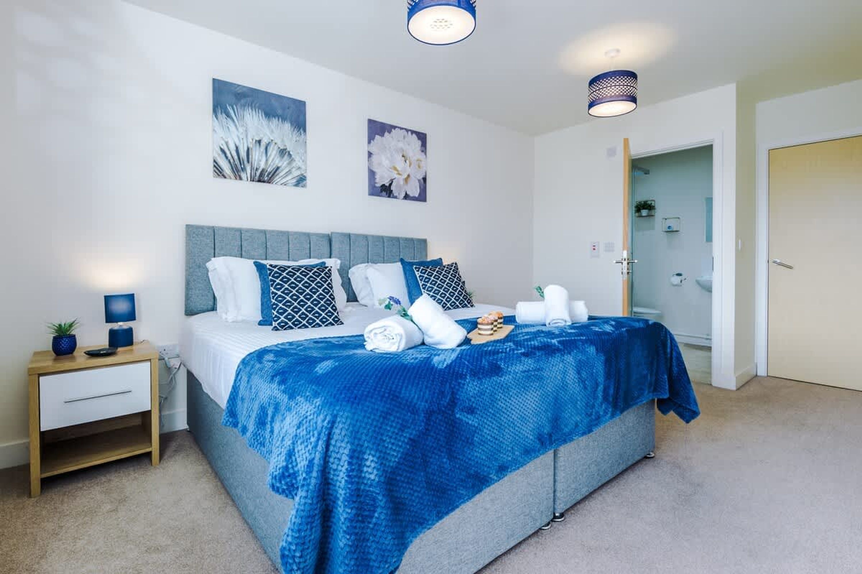Un dormitorio ordenado con cama, mesita de noche y decoración en la pared.