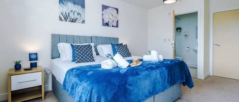 Un dormitorio ordenado con cama, mesita de noche y decoración en la pared.