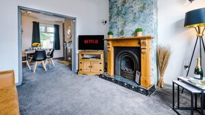 Ein Wohnzimmer mit Kamin, Fernseher und Essbereich.