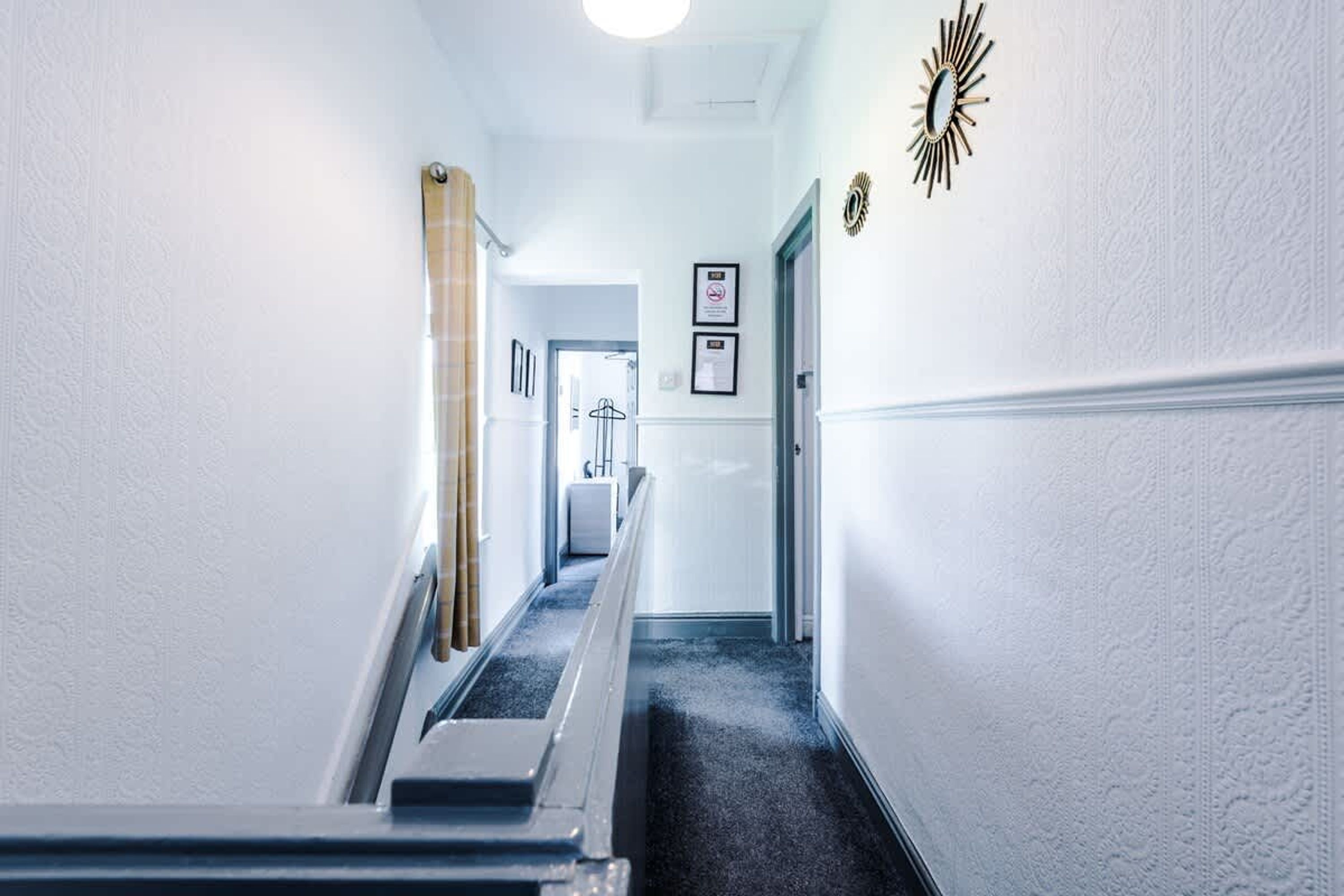 A hallway with a carpeted floor, a handrail, and a door at the end.