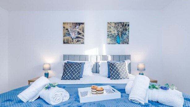 Ein Hotelzimmer mit einem Bett, zwei Wandleuchten, einer Etagere mit Gebäck und Handtüchern.